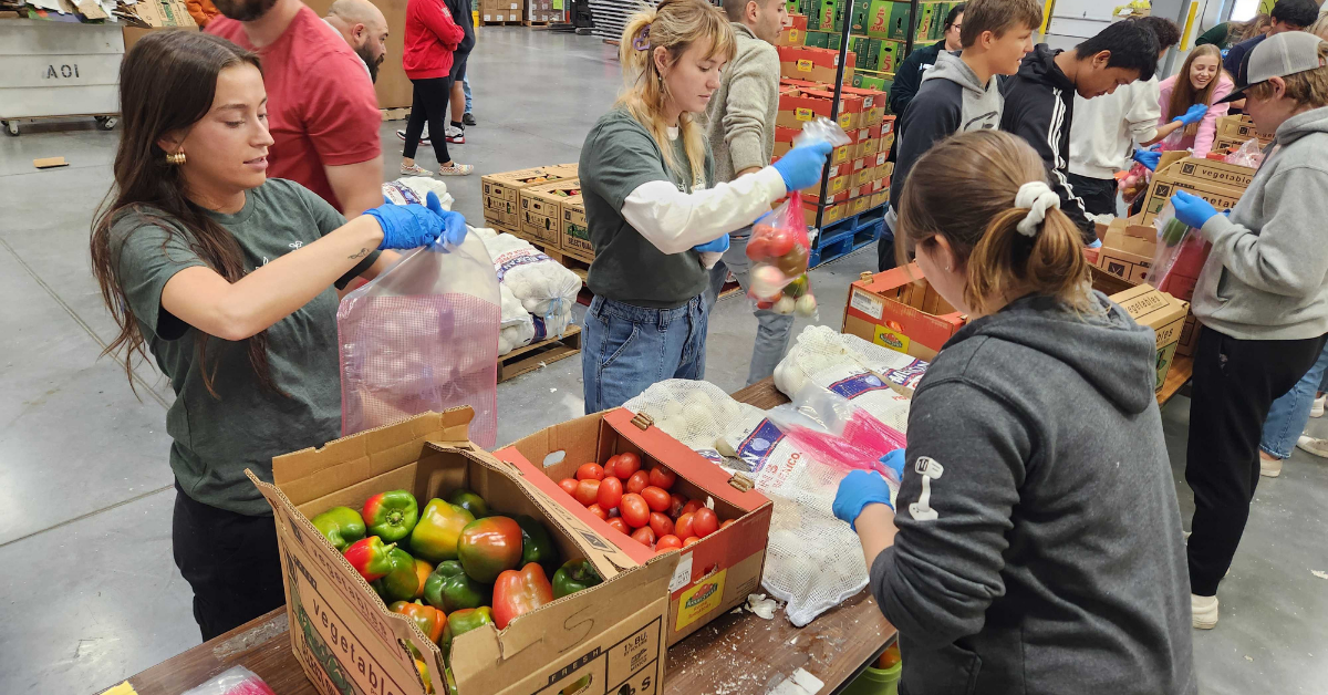 A photo of volunteers from Social Assurance at Lincoln's Food Bank. They are organizing and packaging food donations.